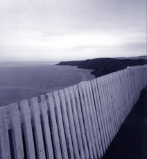 fence along clifftop overlooking ocean and islands