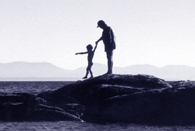 woman and child hopping from rock to rock in the ocean