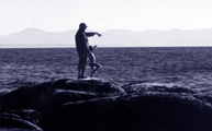 woman and child on rocks in ocean pointing to next rock